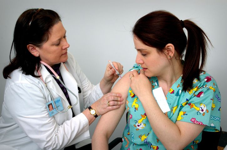 adult female healthcare professional as she was receiving an intramuscular vaccination 725x479